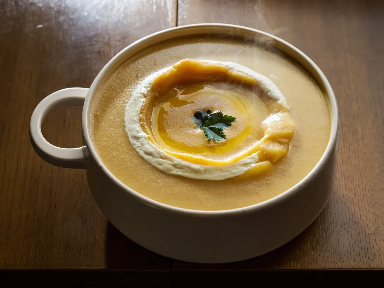 Vellutata di zucca e patate in ciotola di ceramica con filo d'olio e prezzemolo